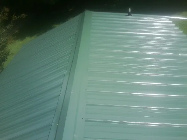 New green metal panels meeting at the ridge of a roof — Flat Roof Repair work by our crew in Berryton