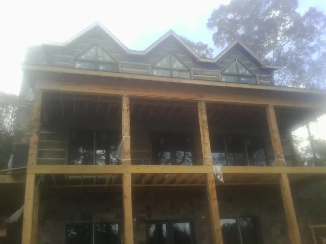 Dormers and porch framing on a large log home under construction — Roof Coating work by our crew in Berryton