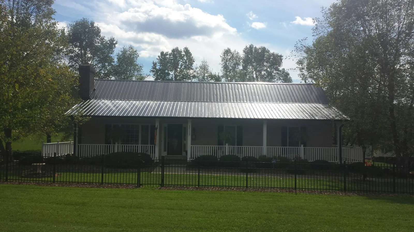 Gray metal roof on a brick ranch with a full width front porch — Gutter Guard Installation work by our crew in Berryton