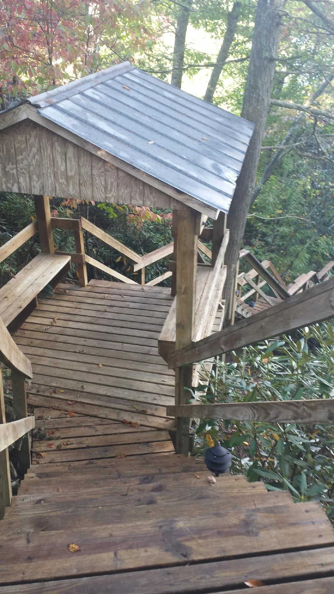 Metal roofed shelter over wooden steps on a wooded walkway — Skylight Repair & Installation work by our crew in Berryton