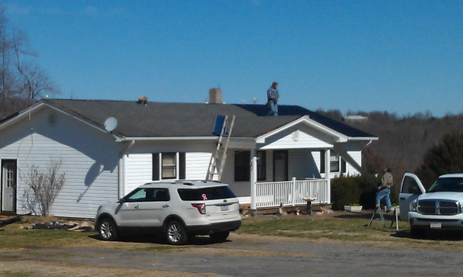 Roofers stripping shingles from a white ranch house roof in Berryton